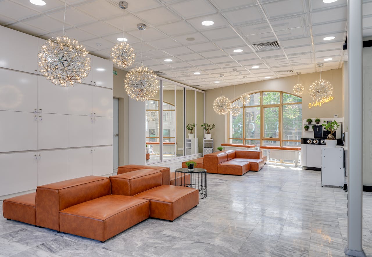 Spacious office lounge with leather couches and hanging lights.